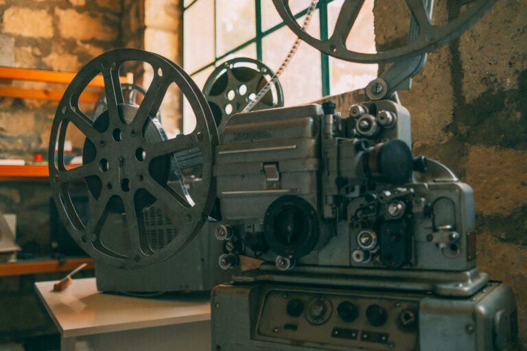 Close-up of a vintage film projector in a rustic, dimly lit room with stone walls.