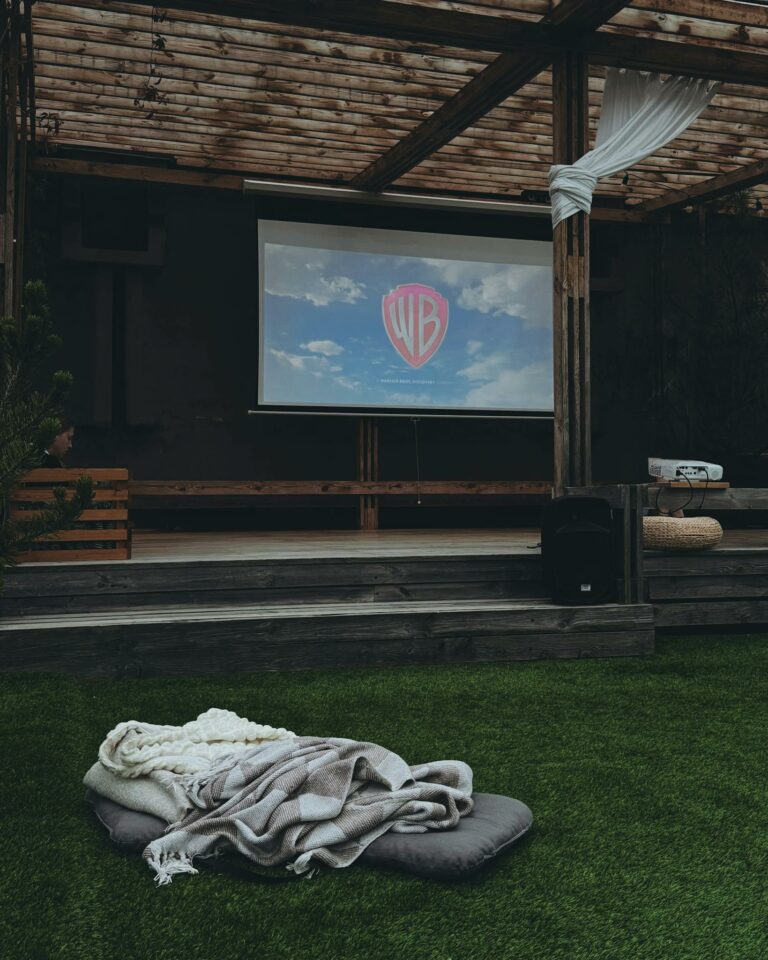 Outdoor cinema with comfy seating and a projector screen for a cozy movie night experience.